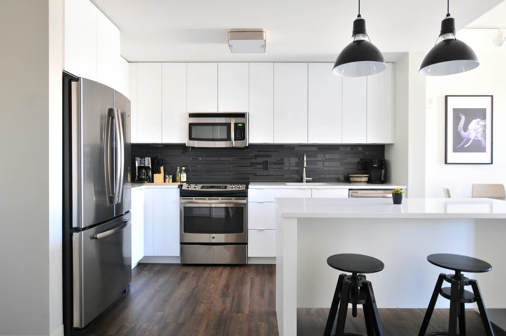 Modern kitchen in a Regina home with a stainless steel refrigerator, range, and over-the-range microwave.